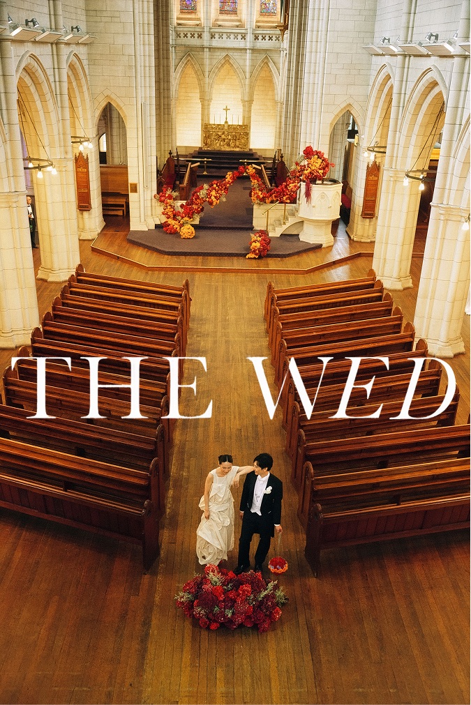 The Wed cover: a couple in a church aisle with deep red florals along the chancel steps