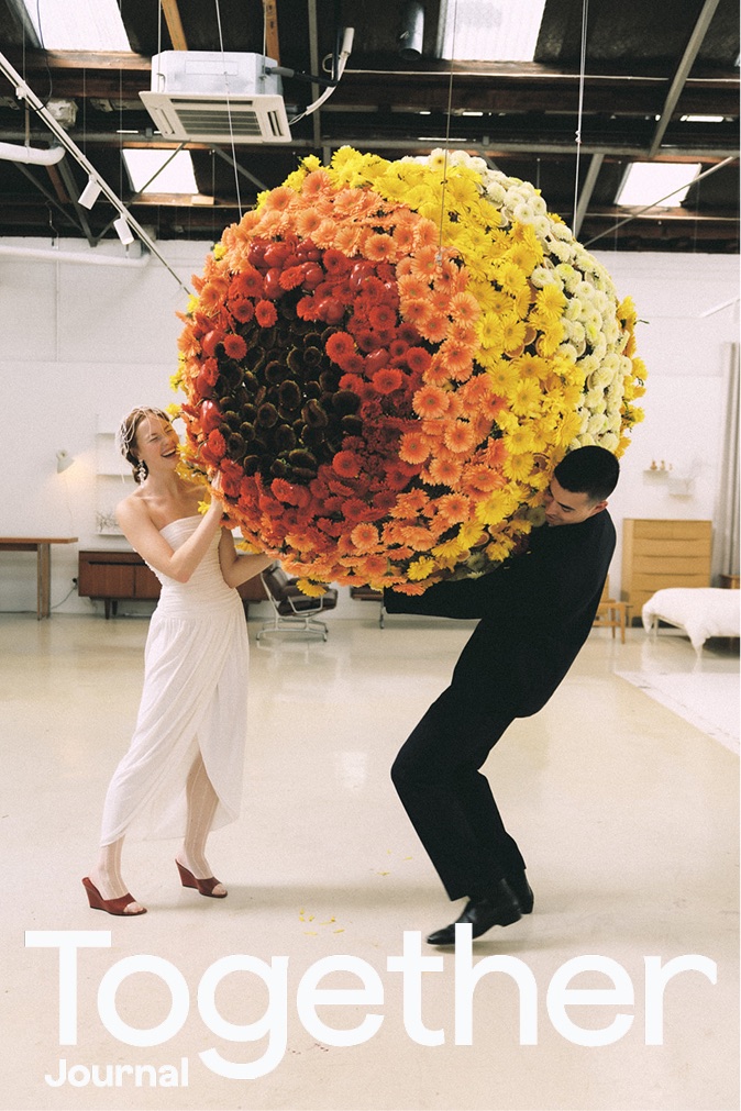 Together Journal cover: a couple carrying a suspended sphere of orange and yellow chrysanthemums